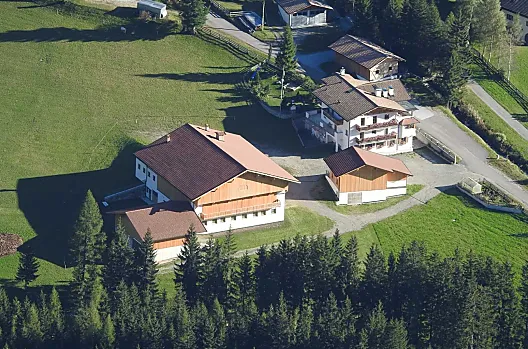 L'Huterhof in estate: qui si può vedere l'edificio del maso di nuova costruzione e la casa residenziale con il parco giochi alle spalle.