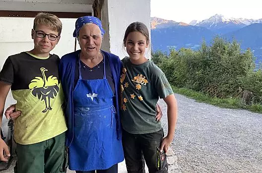 La vecchia contadina Cilli con i bambini ospiti dopo la mungitura nella stalla. Gli Stocker sono sempre felici di condividere la vita del maso con i loro ospiti.