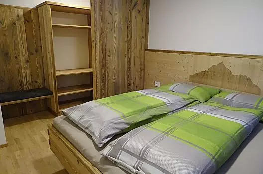 Camera da letto con immagini dello Sciliar e cabina armadio nell'appartamento vacanze "Butterfly