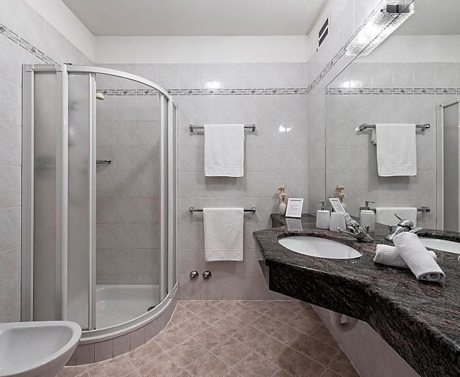 Ein klassisches Badezimmer mit Dusche, Bidet/WC und Waschbecken mit großer Ablagefläche aus echtem Marmorstein