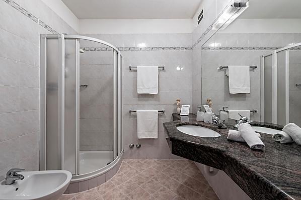 Ein klassisches Badezimmer mit Dusche, Bidet/WC und Waschbecken mit großer Ablagefläche aus echtem Marmorstein