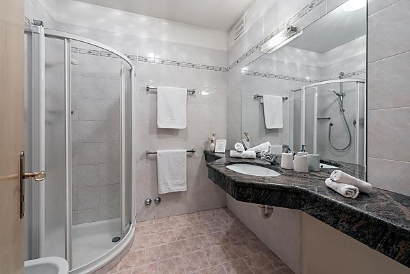 Ein klassisches Badezimmer mit Dusche, Bidet/WC und Waschbecken mit großer Ablagefläche aus echtem Marmorstein