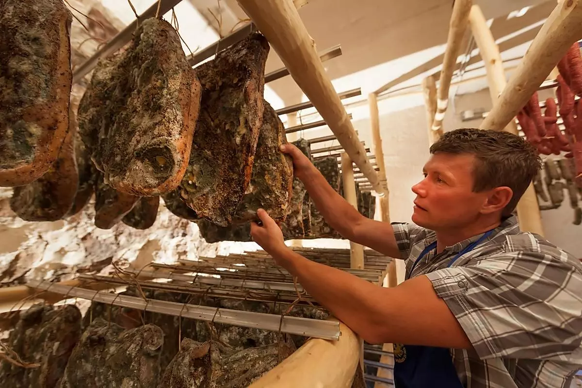 Speck e salsicce affumicati appesi a bastoni