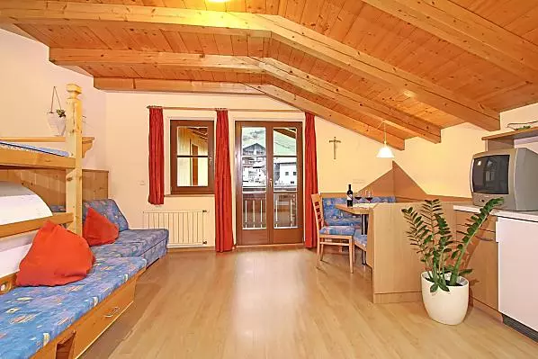 Wohnraum mit ausziehbarer Couch und traditionellem Bauernofen