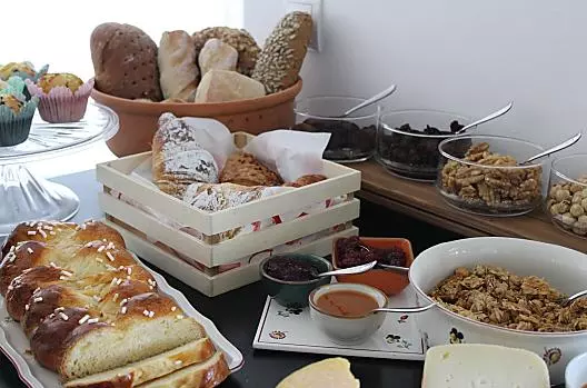 Colazione con treccia di pasta lievitata fatta in casa, muffin, marmellate e granola.