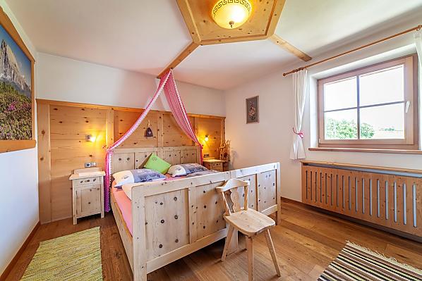 Schlafzimmer mit Doppelbett, Holzboden und Möbeln aus Zirbenholz.