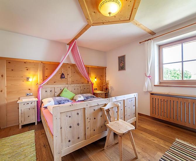 Schlafzimmer mit Doppelbett, Holzboden und Möbeln aus Zirbenholz.