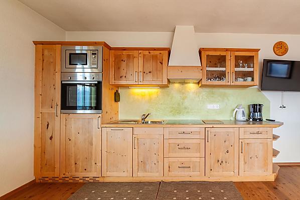 Küchenzeile mit Mikro, Backofen, Kühlschrank mit Gefrierfach, Spülmaschine und Elektrokochfeld.