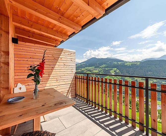 Herrliche Aussicht zu den Dolomiten auf dem großen, überdachten Balkon mit Tisch und Liegestuhl.