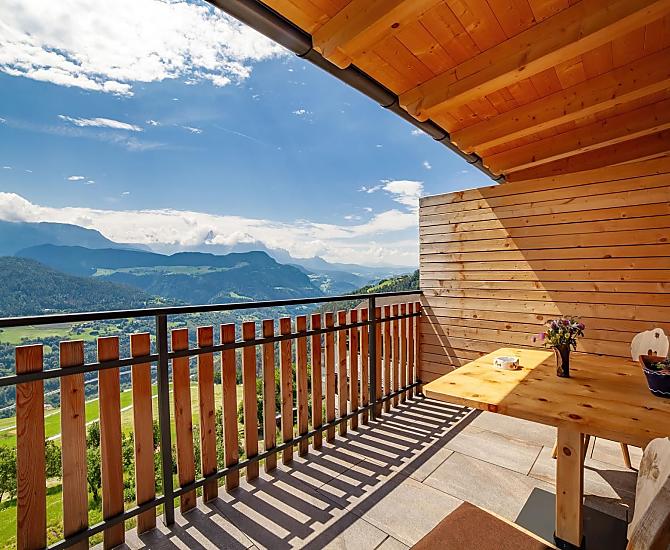 Herrliche Aussicht zu den Dolomiten auf dem großen, überdachten Balkon mit Tisch und Liegestuhl.
