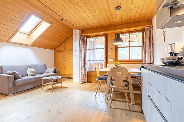 Die Wohnküche mit Eichenboden, Schlafcouch, moderner Küchenzeile und traditioneller Sitzecke aus Fichtenholz aus unserem Wald.