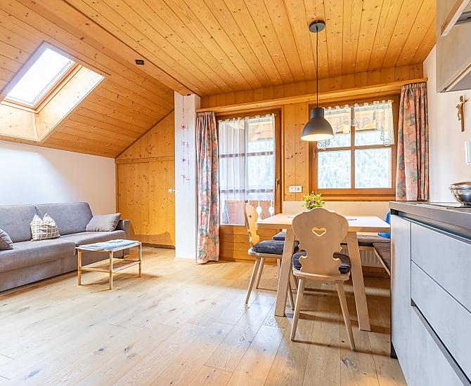 Die Wohnküche mit Eichenboden, Schlafcouch, moderner Küchenzeile und traditioneller Sitzecke aus Fichtenholz aus unserem Wald.