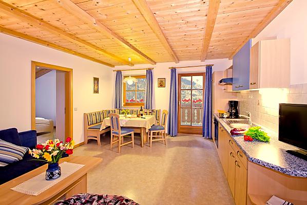 Helle Wohnküche mit Zugang zum Balkon, welcher Ihnen eine herrliche Aussicht zum Schlern und auf die umliegende Bergwelt schenkt.