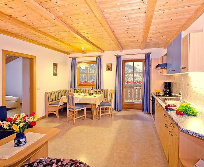 Helle Wohnküche mit Zugang zum Balkon, welcher Ihnen eine herrliche Aussicht zum Schlern und auf die umliegende Bergwelt schenkt.