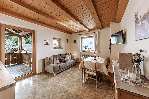 Liebevoll eingerichtete Wohnküche mit Couch, TV und Terrasse (Morgensonne).
