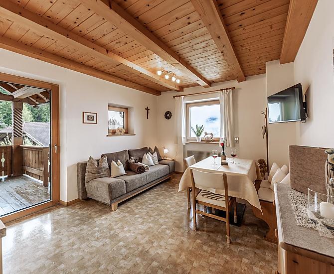 Liebevoll eingerichtete Wohnküche mit Couch, TV und Terrasse (Morgensonne).