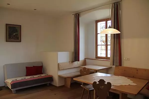 Geräumiger Wohnbereich mit Sofa, Ofen, Nische zum Sitzen sowie Tisch mit Eckbank.