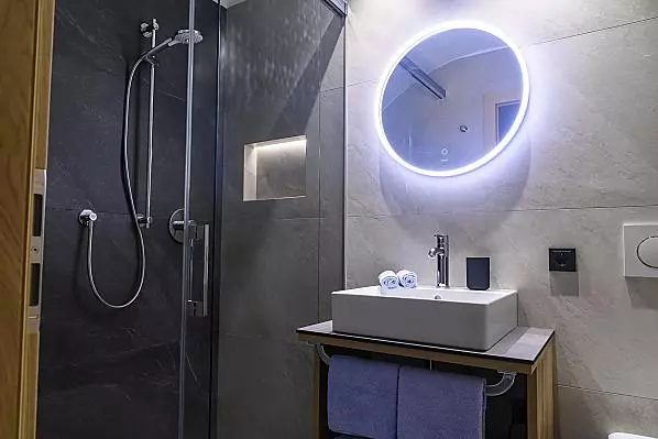 Badezimmer mit Dusche, Waschbecken, WC und Handtuchtrockner.