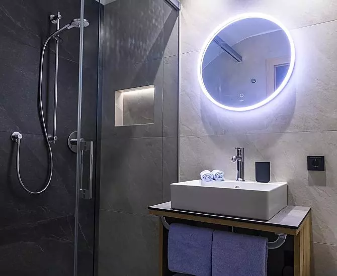 Badezimmer mit Dusche, Waschbecken, WC und Handtuchtrockner.