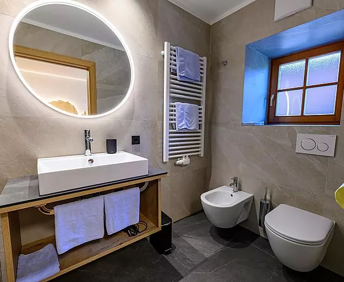 Badezimmer mit Dusche, Waschbecken, Handtuchtrockner, Bidet und WC.