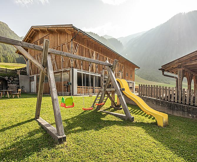 Parco giochi naturale con tante possibilità di divertimento: sabbiera, altalena, scivolo e ampio prato per giocare.
