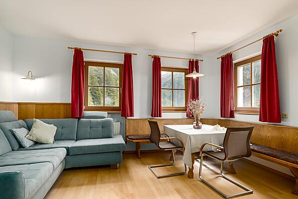 Großes Wohnzimmer mit großer ausziehbarer Couch und Eckbank mit Tisch.