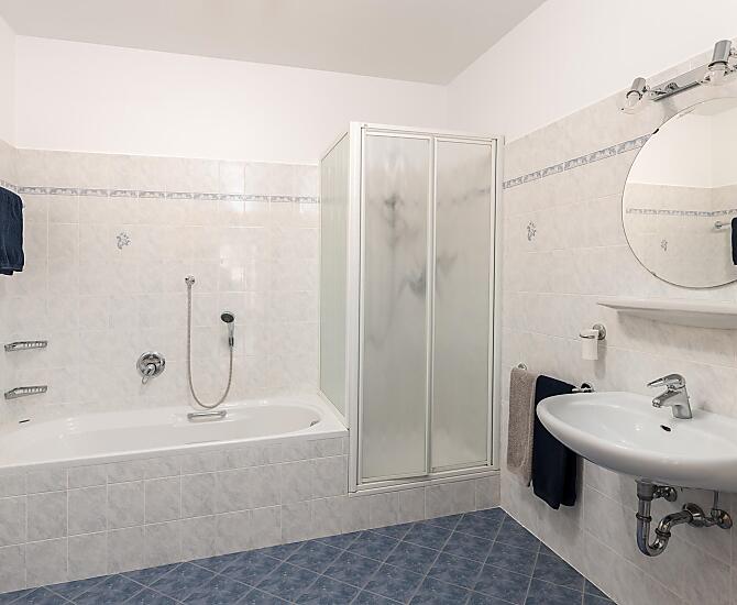 Großes Bad mit Badewanne, Dusche, Bidet und WC.