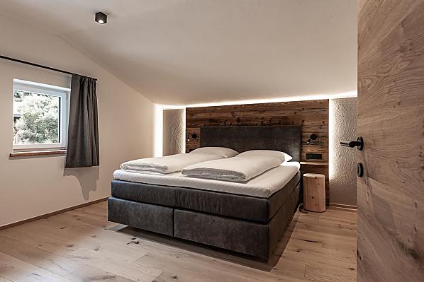Schlafzimmer mit Holzboden und Akzenten aus Altholz.