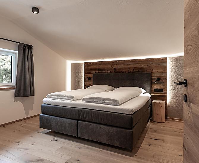 Schlafzimmer mit Holzboden und Akzenten aus Altholz.