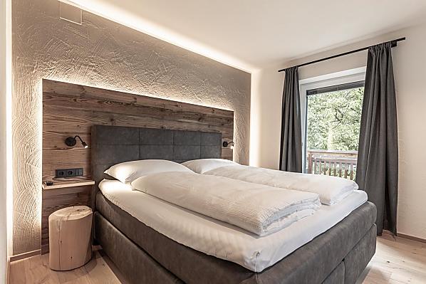 Schlafzimmer mit Holzboden und Akzenten aus Altholz.
