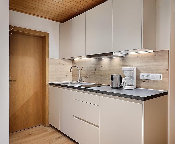 Küchenzeile mit Geschirrspüler, Kühlschrank mit Gefrierfach, Kaffeemaschine, Toaster, Mixer, Sat-TV, Herdplatte und Mikrowelle.