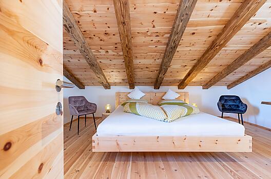 Accogliente letto matrimoniale in legno di cirmolo – profumo naturale e fascino alpino per notti rigeneranti.