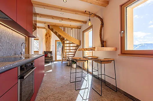 Cucina luminosa, pietra naturale sotto i piedi e montagne così vicine da sembrare a portata di mano.