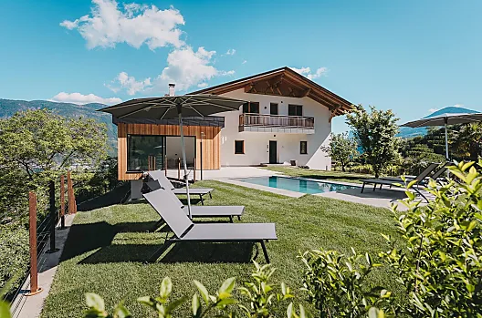 Idilliaco maso biologico con piscina e lounge per gli ospiti, immerso tra prati, meleti e vigneti, un angolo di natura ricco di vita e colori.