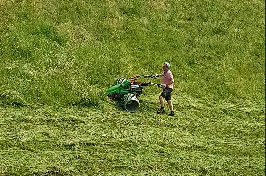 Il padrone di casa e contadino Herbert taglia l'erba dei nostri ripidi prati di montagna con la motofalciatrice.