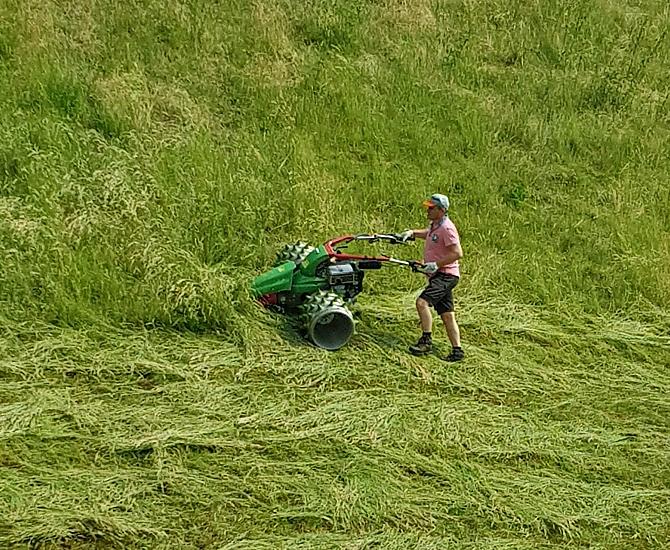 Il padrone di casa e contadino Herbert taglia l'erba dei nostri ripidi prati di montagna con la motofalciatrice.