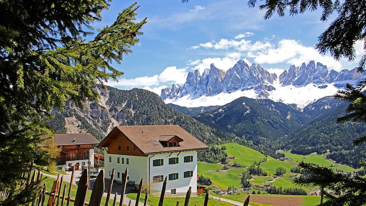 Vista del maso in primavera con la neve sul gruppo delle Odle
