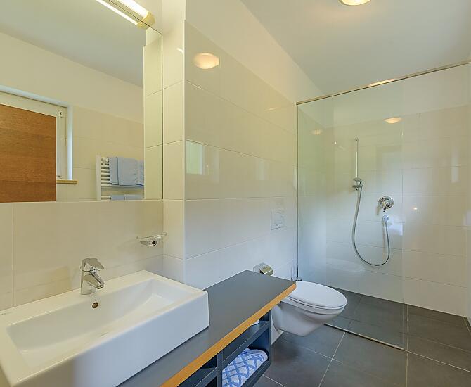 Helles, großes Badezimmer mit begehbarer Dusche/WC, Föhn, Handtücher, Badetücher, vom Schlafzimmer aus zugänglich.