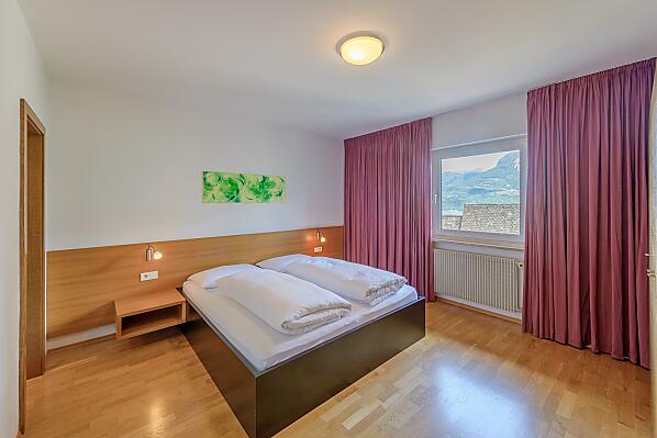 Geräumiges Doppelzimmer mit dreiteiligem Schrank, Holzboden, Bettenlänge 200 cm, Safe, direktem Zugang zum Badezimmer und Blick ins Tal.