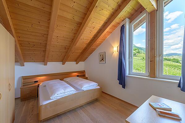 Schlafzimmer mit herrlichem Ausblick auf Tramin, den Poolbereich, in die Weinberge, in die Berge bis zur Sarner Scharte und aufs Weisshorn